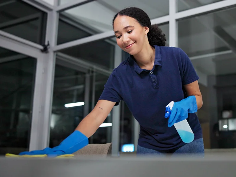 Femme entrain de nettoyer un bureau avec le sourire